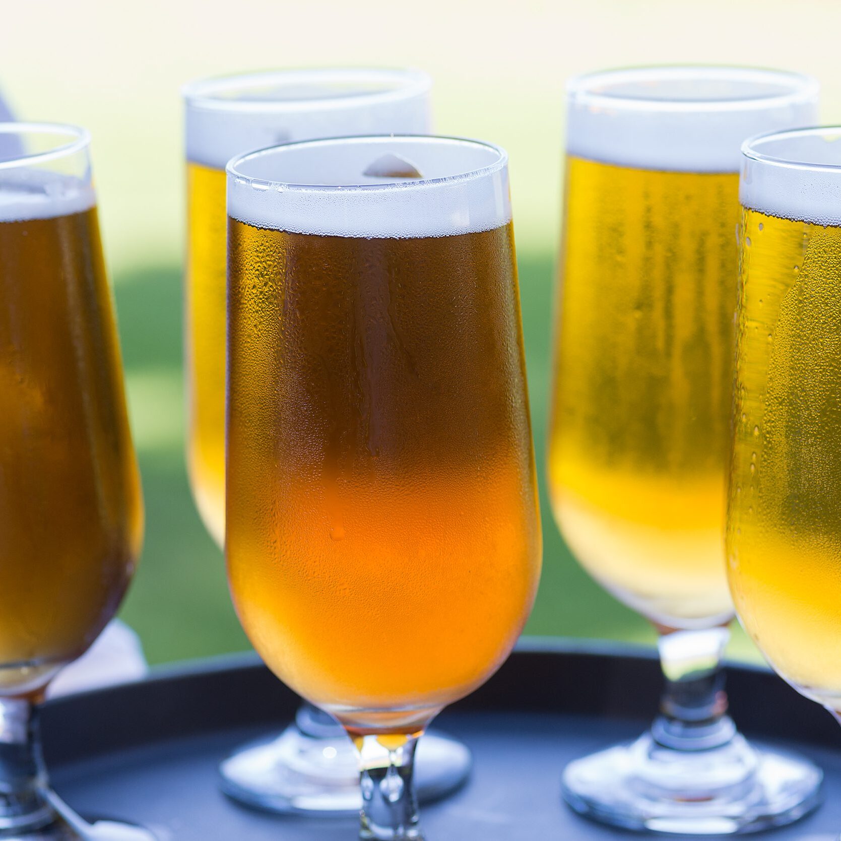 Schooner glasses of ice cold beer sitting on a black service tray